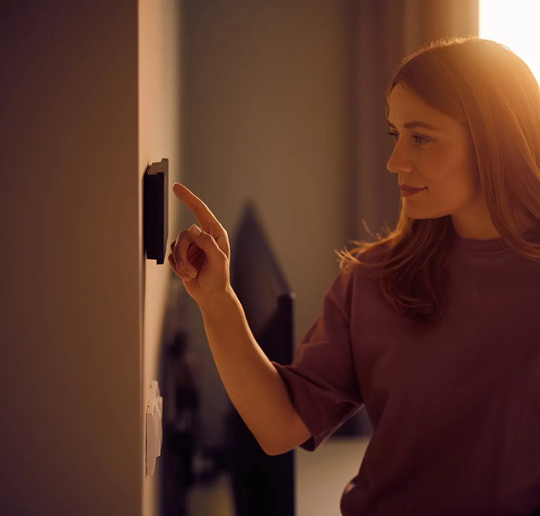 Woman controlling an electrical device on the wall